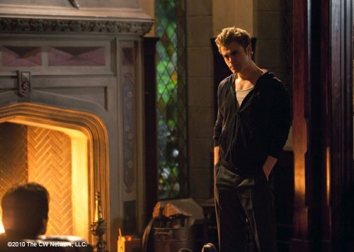 Stefan et  Damon discutent devant la cheminée