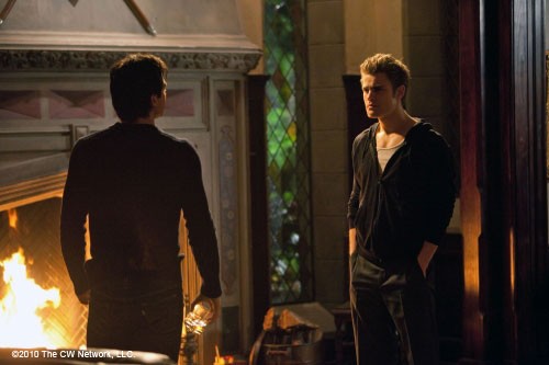 Stefan et  Damon discutent devant la cheminée